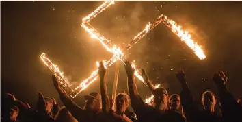  ?? (Go Nakamura/Reuters) ?? SUPPORTERS OF THE National Socialist Movement give Nazi salutes while taking part in a swastika-burning in Georgia in April.