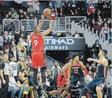  ?? NICK WASS THE ASSOCIATED PRESS ?? Raptors’ Serge Ibaka shoots late in double overtime over Wizards’Otto Porter Jr. and Tomas Satoransky on Sunday. Toronto won, 140-138.