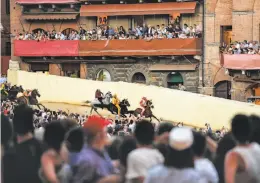  ??  ?? Top, Jonatan Bartoletti balances atop his horse Sarbana at last month’s race — Il Palio to locals — in the Tuscan city of Siena. Above, riders navigate the course during one of the three laps in the race, which will be contested again Aug. 16.