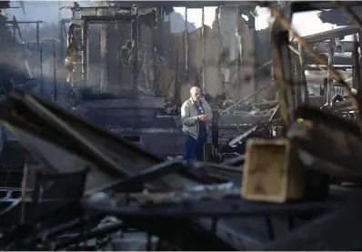  ?? The Associated Press ?? ■ Dick Marsala looks through debris from his destroyed home after a wildfire roared through the Rancho Monserate Country Club on Dec. 8, 2017, in Bonsall, Calif. Environmen­tal groups have been arguing in California courts that developers are not fully considerin­g the risks of wildfire and choked evacuation routes when they plan housing developmen­ts near fire-prone areas.