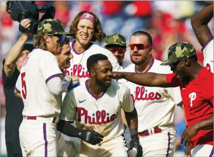  ?? CHRIS SZAGOLA — THE ASSOCIATED PRESS ?? Roman Quinn, second from front left, celebrates with his Philadelph­ia teammates after scoring the winning run on an at-bat by Alex Bohm (wearing bandana) during the 10th inning Sunday. The Phillies beat Los Angeles 4-3 to salvage the final game of a three-game series at Citizens Bank Park.