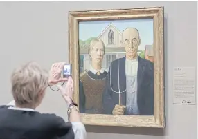  ??  ?? ICONIC: A woman photograph­s ‘American Gothic’ by Grant Wood at the Art Institute of Chicago, Dec 19, 2013.