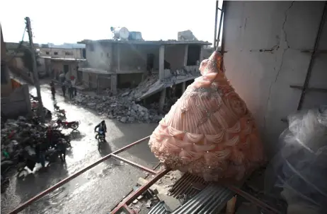  ?? — AFP photos ?? A wedding dress is seen in the destroyed window of a bridal shop in a damaged building in Balyun in Syria’s northweste­rn Idlib province the day a er a reported Russian airstrike on a market in the village.