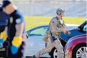  ?? JOHN MCCALL/STAFF FILE PHOTO ?? A law enforcemen­t officer rushes toward Marjory Stoneman Douglas High School Feb. 14. Police looking for the shooter were also hampered by radio transmissi­on failures.