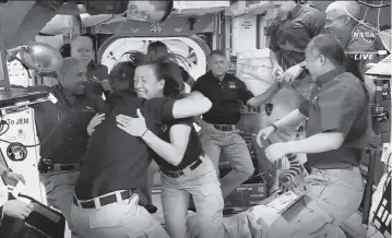  ?? NASA via AP ?? Astronauts from SpaceX are greeted by the astronauts from the Internatio­nal Space Station after the Dragon capsule successful­ly docked Saturday. The recycled SpaceX capsule carrying four astronauts has blasted off from Cape Canaveral a day earlier.