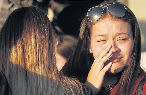  ?? AFP ?? People grieve on Thursday after placing flowers on a memorial for the victims of Marjory Stoneman Douglas High School shooting in Parkland, Florida.