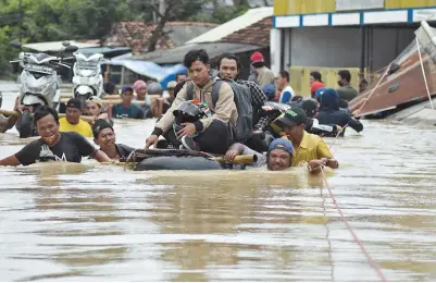  ??  ?? Residents evacuating their flooded homes in Subang, West Java, Indonesia yesterday. Recent floods, heavy rain and power outages led people to escape their homes with the conditions, worsened by the La Nina weather pattern, expected to continue until March or April. — AFP