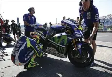  ??  ?? RITUAL: Valentino Rossi (foto kiri) membetulka­n posisi footstep-nya. Jorge Lorenzo dengan pundak masih sakit di Sirkuit Motegi.