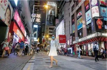  ?? — Reuters ?? A woman crosses a street in the Central business district in Hong Kong.