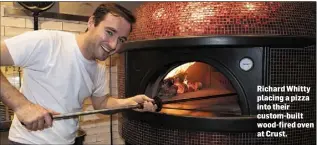  ??  ?? Richard Whitty placing a pizza into their custom-built wood-fired oven at Crust.