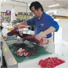  ?? MARI YAMAGUCHI/THE ASSOCIATED PRESS ?? A fish retailer at the Onahama fish market in Iwaki City, Fukushima, cuts up tuna from Miyazaki, southern Japan, amid slumping demand for Fukushima fish.