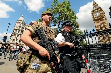  ?? PHOTO: REUTERS ?? A soldier and police officer walk past the Houses of Parliament in London as security patrols are increased following the Manchester bombing.