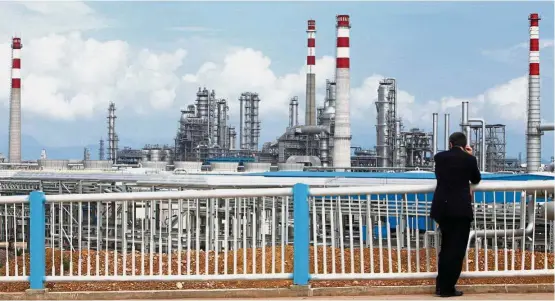  ?? — Reuters ?? Big capex: A file picture showing a visitor looking at CNOOC’s oil refinery in Huizhou. The company sees capex of up to US$12.7bil for this year.