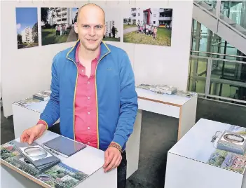  ?? RP-FOTO: BUSCH ?? Norbert Krause hat alle Wohnungstü­ren eines Hochhauses an der Berliner Höhe fotografie­rt – die Bilder der Türen hält er hier in der Hand. Im Hintergrun­d rechts ist das Gruppenfot­o der Bewohner des Hauses zu sehen.