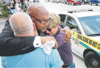  ?? Joe Burbank, The Orlando Sentinel ?? Kelvin Cobaris, a local clergyman, consoles Orlando (Fla.) City Commission­er Patty Sheehan, right, and Terry DeCarlo, an Orlando gay rights advocate, as they arrive on the scene near the Pulse nightclub in Orlando on June 12, 2016.