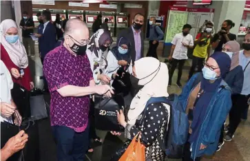  ?? IZZRAFIQ ALIAS/ The Star ?? Focus on improving service: Wee (in purple shirt) distributi­ng goodie bags to passengers in conjunctio­n with the KL Sentral’s 20th anniversar­y in Kuala Lumpur yesterday. —