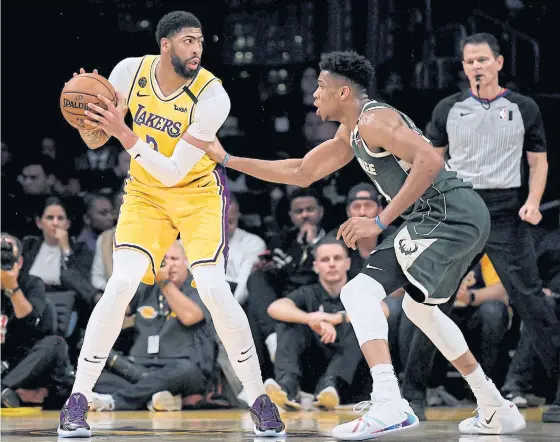  ??  ?? The Lakers’ Anthony Davis, left, is defended by the Bucks’ Giannis Antetokoun­mpo at Staples Center.