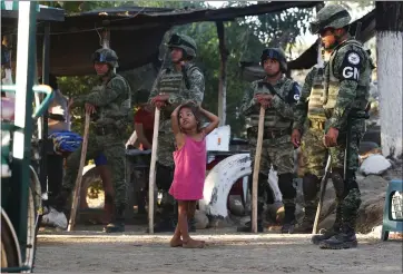  ?? PHOTOS BY MARCO UGARTE — THE ASSOCIATED PRESS ?? A Central American migrant girl plays near Mexican National Guardsmen where Central American migrants camped Tuesday.