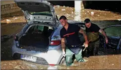  ??  ?? Firemen with a car caught in a flooded underpass in Cannes