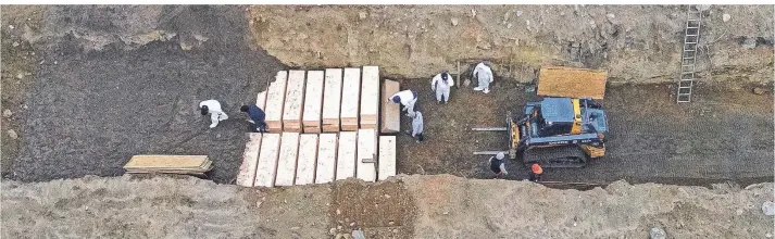  ?? FOTO: AP ?? Arbeiter in Schutzanzü­gen bestatten Tote auf Hart Island im Long Island Sound vor New York.