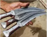  ??  ?? A Yemeni man holds newly-formed daggers, created by recycling scrap metal of fallen rockets.