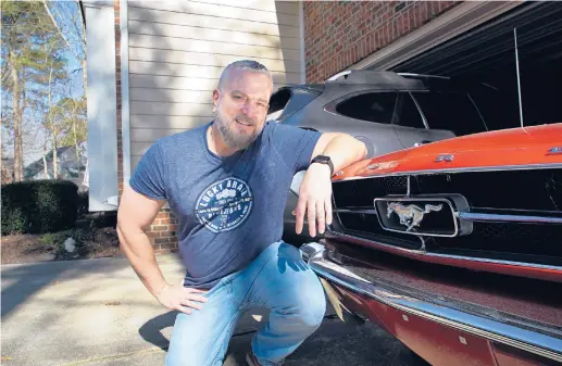  ?? ALLEN G. BREED/AP ?? Steve Bock kneels beside his 1965 Ford Mustang at his home in Apex, North Carolina. He recently bought a Subaru Outback, but would like to have an electric or hybrid car if they were cheaper. Electric vehicles make up less than 2% of new vehicle sales in the U.S.