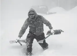  ?? DEREK GEE The Buffalo News via AP ?? Travis Sanchez trudges over a snowdrift with a pair of shovels to assist a stranded motorist on Chenango Street in Buffalo, N.Y. on Saturday.