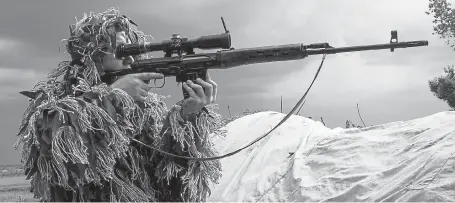  ?? Mstyslav Chernov, Associated Press file ?? A Russia-backed rebel looks through the sights of a sniper rifle toward Ukrainian positions near Dokuchayev­sk, eastern Ukraine. During the past month or so, Russia has deployed what analysts are calling its largest military buildup along the border with Ukraine.