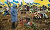  ?? AP ?? The wife of slain Ukrainian serviceman Serhiy Klymenko stands by his grave Friday in Kharkiv, Ukraine. Klymenko was killed by Russian shelling earlier in the week.