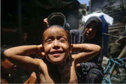  ?? Photograph: Majdi Fathi/NurPhoto/ REX/Shuttersto­ck ?? A Palestinia­n mother showers her child during a heatwave in the southern Gaza Strip in August 2022.