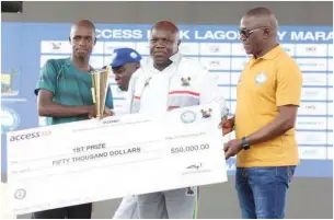  ??  ?? Governor of Lagos State, Akinwunmi Ambode (C) and minister of sports, Solomon Dalung (R) presenting the cheque of $50,000 to winner of the 2018 Lagos City Marathon, Abraham Kiprotich