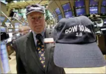  ?? RICHARD DREW — THE ASSOCIATED PRESS FILE ?? Arthur Cashin, director of floor operations for UBS Financial Services, wears his 1999 “Dow 10,000” cap, while holding the 2009 2.0 version, on the floor of the New York Stock Exchange. If stocks don’t drop significan­tly by the close of trading Wednesday the bull market that began in March 2009 will have lasted nine years, five months and 13 days, a record that few would have predicted when the market struggled to find its footing after a 50 percent plunge during the financial crisis.