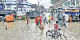  ?? PTI ?? People cross a waterlogge­d street during high tide in Kolkata on Thursday.