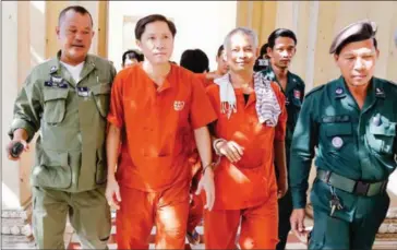  ?? HENG CHIVOAN ?? Adhoc’s Ny Sokha (centre left) and Yi Soksan (centre right) are escorted through the ground of the Phnom Penh Appeal Court yesterday afternoon ahead of their hearing.