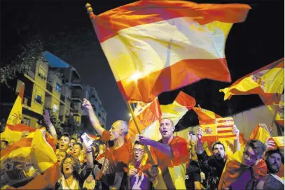  ?? Manu Fernandez ?? The Associated Press Anti-independen­ce demonstrat­ors wave Spanish flags Thursday in support of Spain’s security forces in front of a Guardia Civil (Civil Guard) barracks in Sant Boi de Llobregat on the outskirts of Barcelona, Spain.