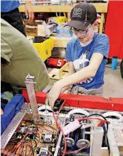  ?? [PHOTOS BY PAUL HELLSTERN, THE OKLAHOMAN] ?? Tyler Hampton, with the Edmond North High School team “Cyberian Huskies,” replaces bumpers on his team’s robot.