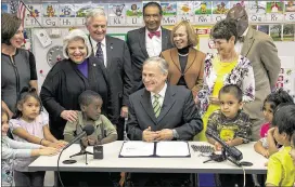  ?? RALPH BARRERA / AMERICAN-STATESMAN ?? Gov. Greg Abbott signs House Bill 4 into law Thursday while surrounded by legislator­s, state officials and pre-K children in a classroom at Anita Uphaus Early Childhood Center in Southeast Austin. Abbott has said HB 4 is not intended to expand pre-K...