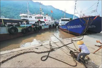  ?? SU QIAOJIANG / XINHUA ?? A fisher secures a vessel at a port in Wenzhou, Zhejiang province, ahead of the expected landfall of Typhoon Yagi in the province late on Sunday night.