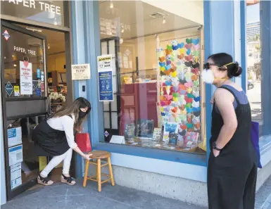  ?? Photos by Paul Kuroda / Special to The Chronicle ?? Linda Mihara, owner of origami shop Paper Tree, sets out a stool on which to place Erica Nobori’s purchase.