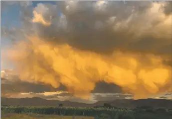  ?? RICK ROMANCITO/For the Taos News ?? A cloud seeding plan that went up in smoke still prompted Taos Pueblo to voice concerns over its managers’ lack of communicat­ion. This photo depicts a Taos cornfield late last summer during a cloudburst over the western
slope of the Sangre de Cristo Mountains, an area that would have been targeted by the proposed plan.