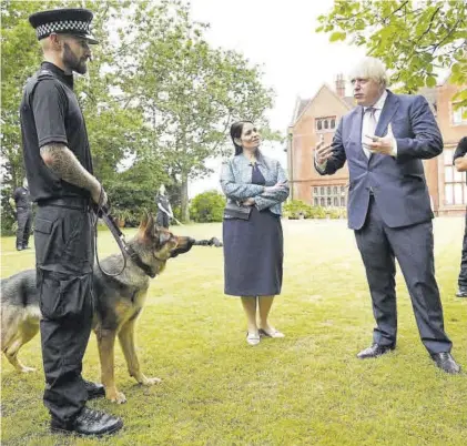  ?? YUI MOK / POOL ?? Boris Johnson departe con un agente durante una visita a la comisaría de la policía de Surrey en Guildford.