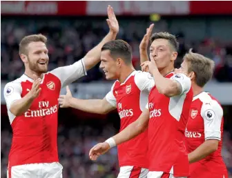  ?? — AFP ?? Arsenal’s Mesut Ozil (second from right) celebrates with teammates after scoring against Chelsea in their English Premier League match at the Emirates Stadium in London on Saturday night. Arsenal won 3-0.