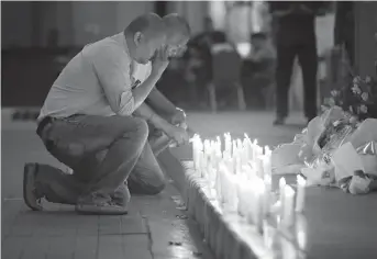  ?? Associated Press ?? A man holds back tears Friday as he lights candles for victims in an attack at the Resorts World Manila complex in Manila, Philippine­s. Police say a gunman stormed a crowded Manila casino and used gasoline to set gambling tables on fire, creating...