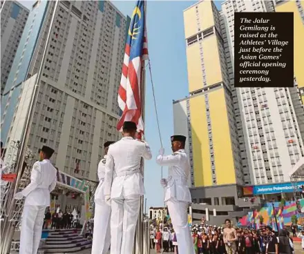  ??  ?? The Jalur Gemilang is raised at the Athletes’ Village just before the Asian Games’ official opening ceremony yesterday.