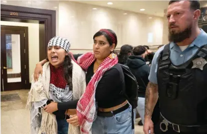  ?? ?? Opponents of Ald. Debra Silverstei­n’s resolution condemning the Hamas attack on Israel are escorted out of the City Council chambers.