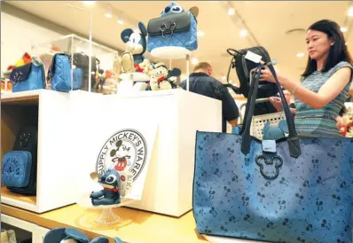  ?? TANG YANJUN / CHINA NEWS SERVICE ?? Visitors examine products at a Disney shop in Shanghai, which opened last week.