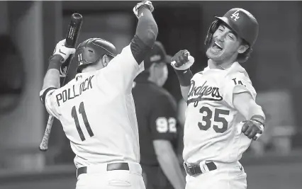  ?? Tom Pennington, Getty Images ?? The Dodgers’ Cody Bellinger is congratula­ted by A. J. Pollock after hitting a solo home run against the Atlanta Braves during the seventh inning in Game 7 of the NLCS at Globe Life Field on Sunday night.