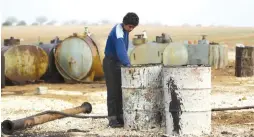  ?? (Khalil Ashawi/Reuters) ?? A YOUTH WORKS at a makeshift oil refinery site in Marchmarin, in the southern countrysid­e of Idlib, Syria.