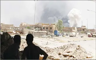  ?? (AFP) ?? Iraqis look at smoke billowing from a building following a reported car bomb in western Mosul’s Zanjili neighbourh­ood
on June 7 during ongoing battles as Iraqi forces try to retake the city from Islamic State (IS) group fighters.