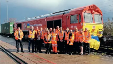  ?? DB Cargo ?? Some of the UK rail industry volunteers who have been involved in organising a train of humanitari­an aid for the Ukraine stand in front of the train. Recently repainted DB Cargo’s 66099 has had the Ukrainian flag colours and #Westandwit­hukraine branding applied on the bodyside of the locomotive.